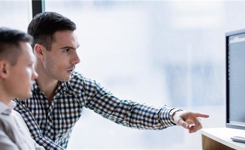 Two businessmen gathered around computer